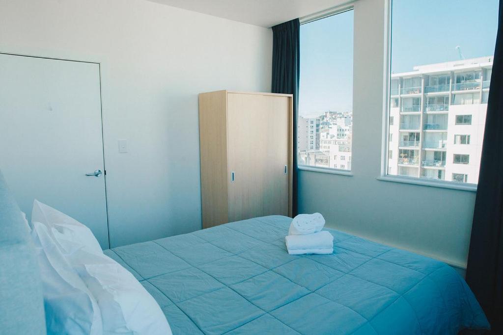 a bedroom with a bed with a teddy bear on it at Liberty Apartment Hotel in Wellington