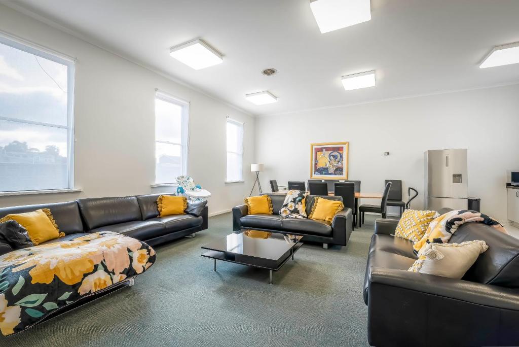 a living room with couches and chairs and windows at 4 Bedroom House - Hobart CBD - Free Parking - Free WIFI in Hobart
