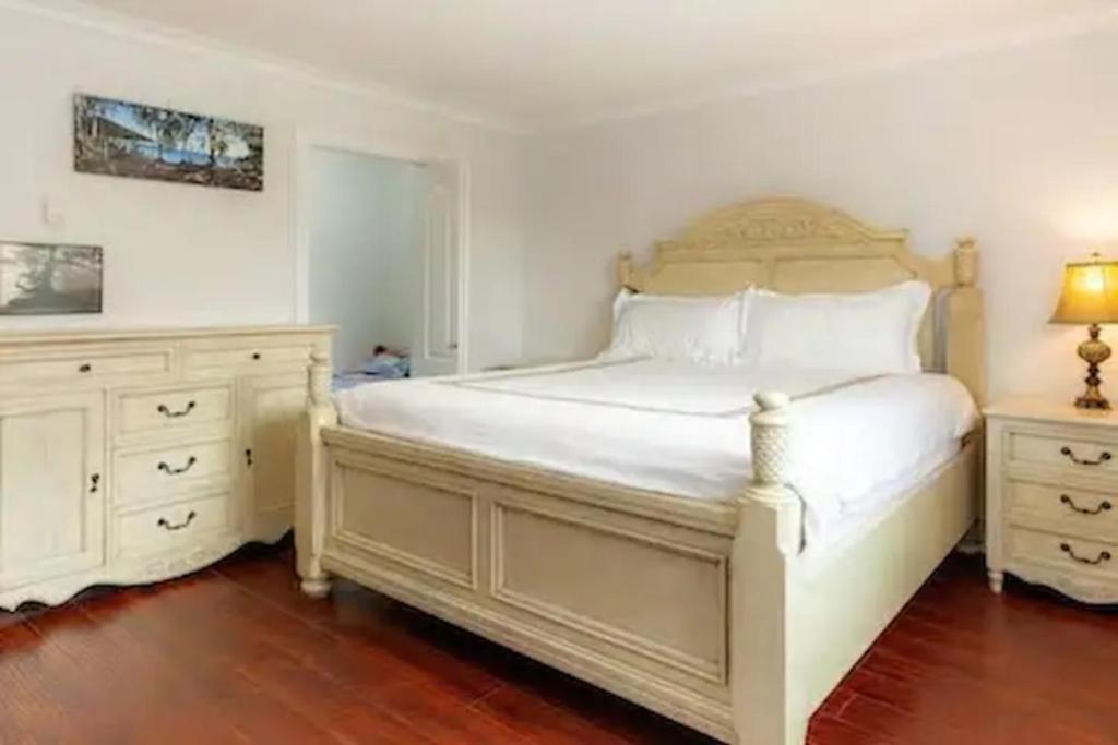 a bedroom with a large white bed and a dresser at John&Jane's House in Surrey