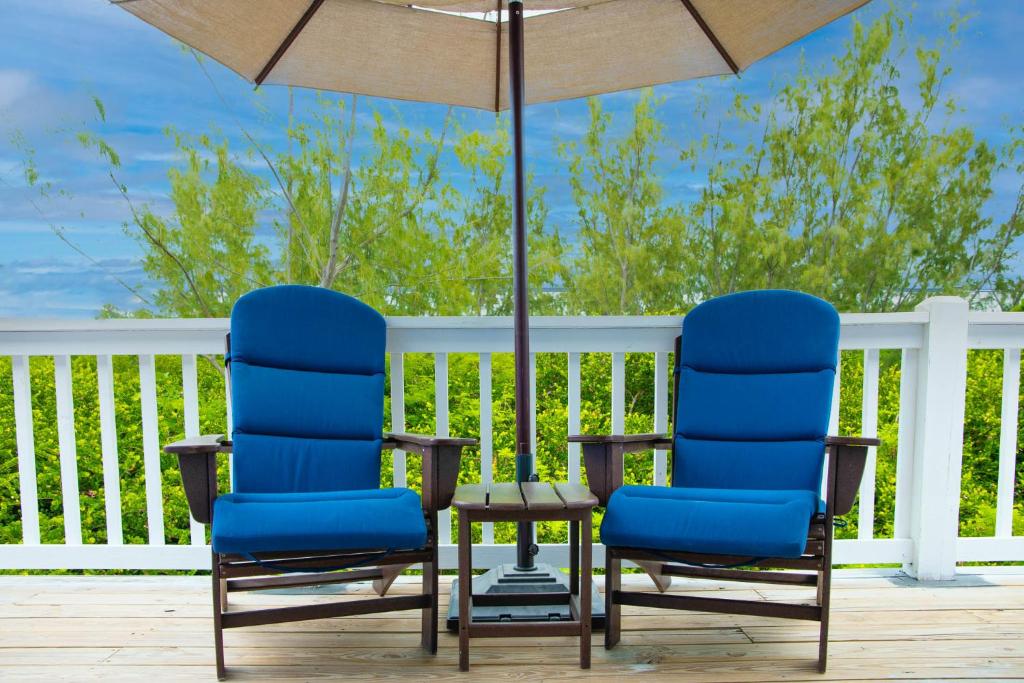 2 chaises et un parasol sur une terrasse dans l'établissement Sheer Bliss BeachView Apt #2, à Exuma Harbour Estates