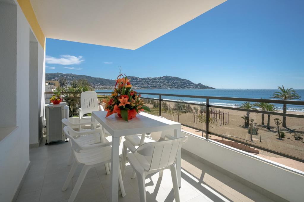 una mesa blanca y sillas en un balcón con vistas al océano en Inmosantos Oasis F5, en Roses