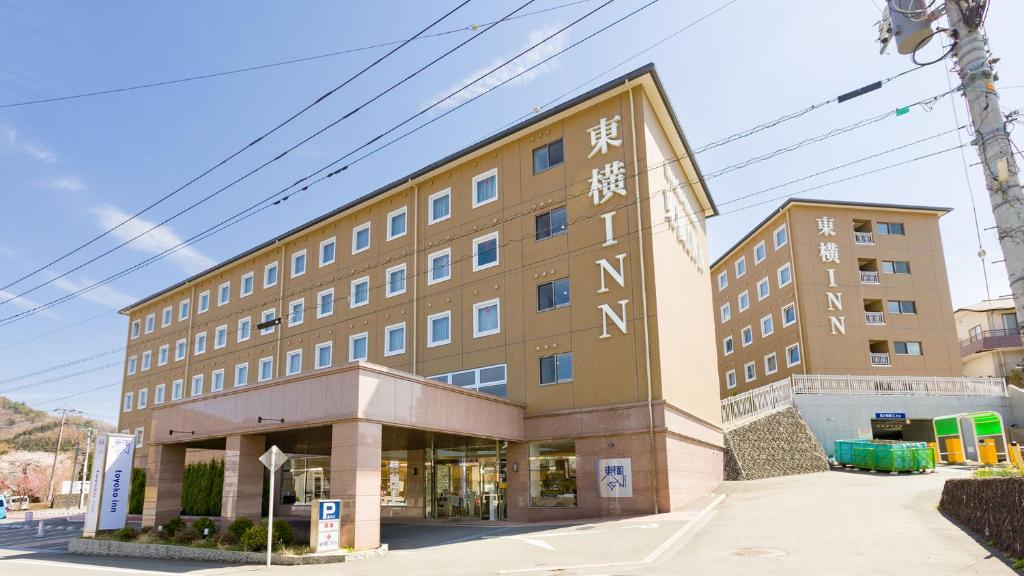 duży budynek z napisem na boku w obiekcie Toyoko Inn Fuji Kawaguchiko Ohashi w mieście Fujikawaguchiko