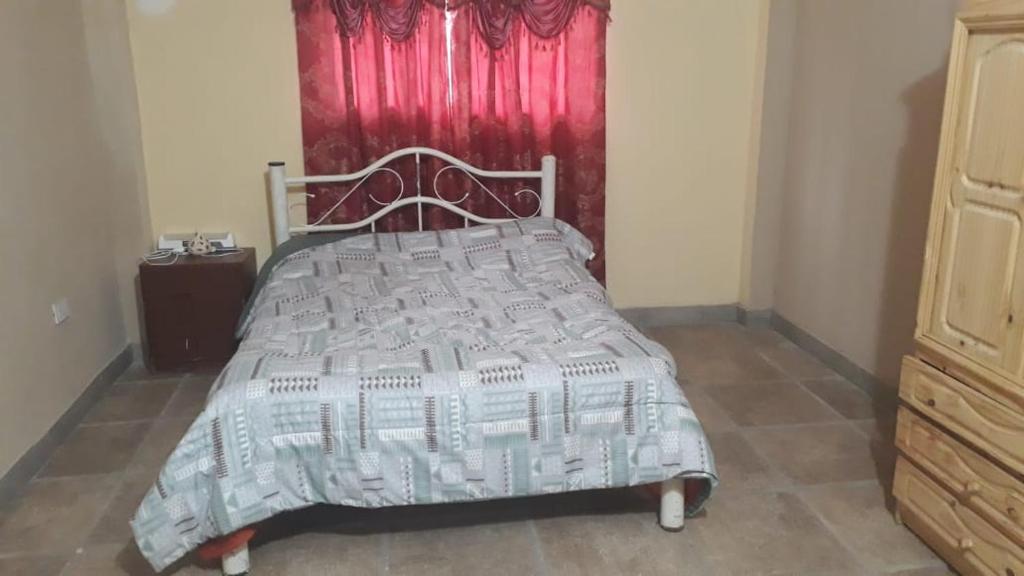 a bed in a bedroom with a red curtain at EL TALAR 1 in Sauce Bajada