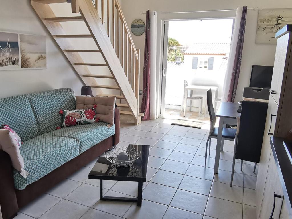a living room with a couch and a staircase at Appartement cosy à 100m de la plage avec mezzanine, terrasse et parking privatif - FR-1-194-263 in La Tranche-sur-Mer