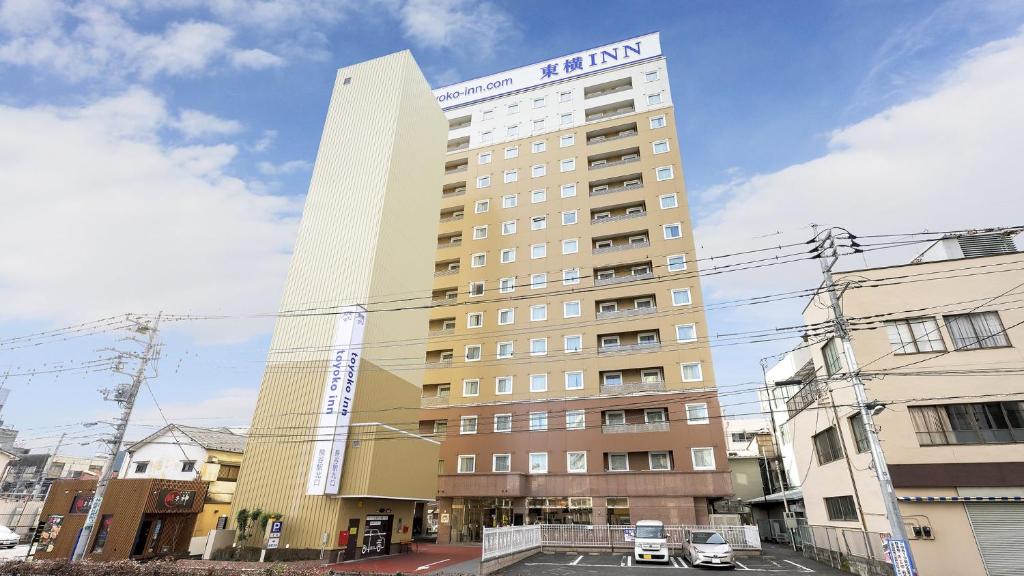 ein hohes Gebäude mit Parkplatz davor in der Unterkunft Toyoko Inn Kumagaya eki Kita guchi in Kumagaya