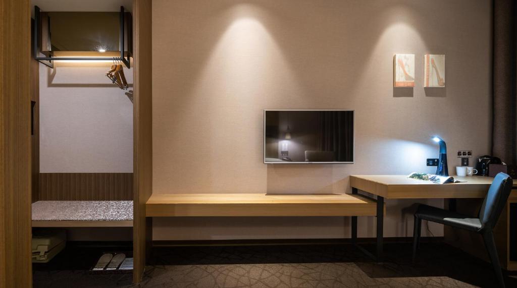 a room with a desk with a tv on a wall at Hotel Intrendy in Taishan