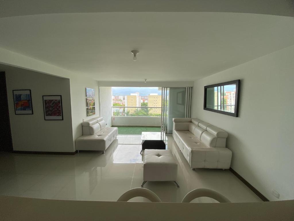 a living room with white furniture and a large window at Apartamento Valle de Lili in Cali