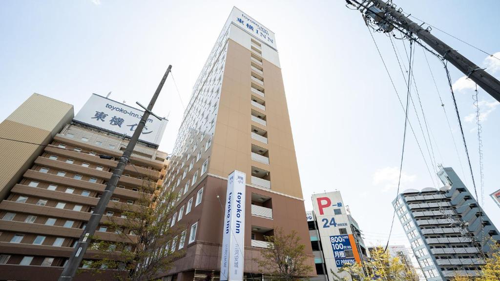 un edificio alto con una grúa delante de él en Toyoko Inn Mikawa anjo eki Shinkansen Minami guchi No 2, en Anjomachi