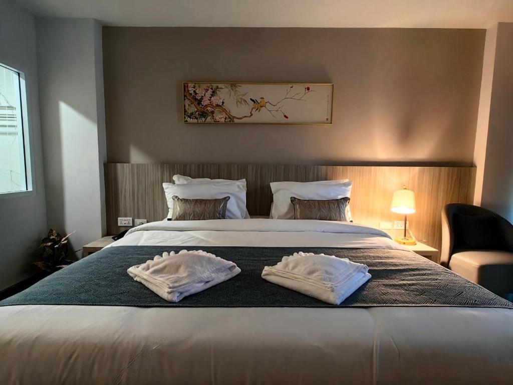 合艾的住宿－Chinatown Living Hatyai，一间卧室配有一张大床和两条毛巾