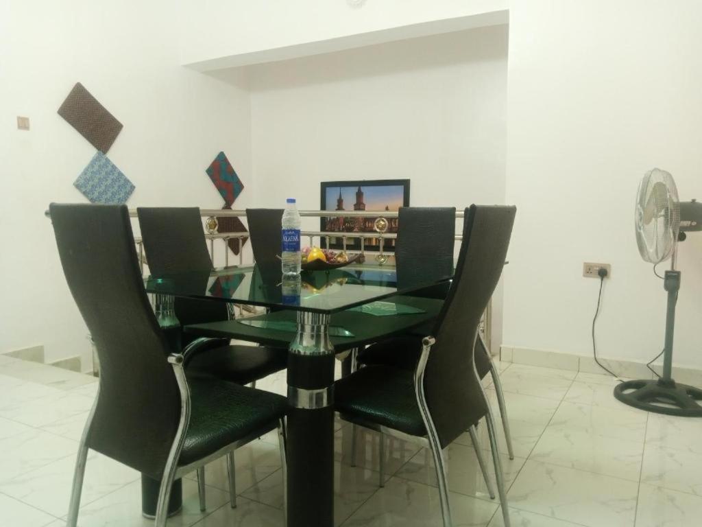 a dining room table with black chairs and a fan at Delad Hotel and Suites in Ibadan
