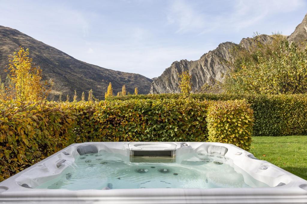a hot tub in a garden with mountains in the background at 61 Gibbston Valley in Gibbston