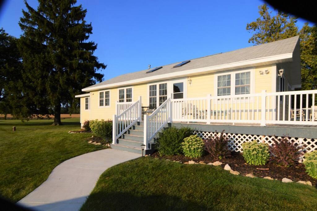 a yellow house with a porch and a walkway at Carraig Dale Cottage in Fish Creek