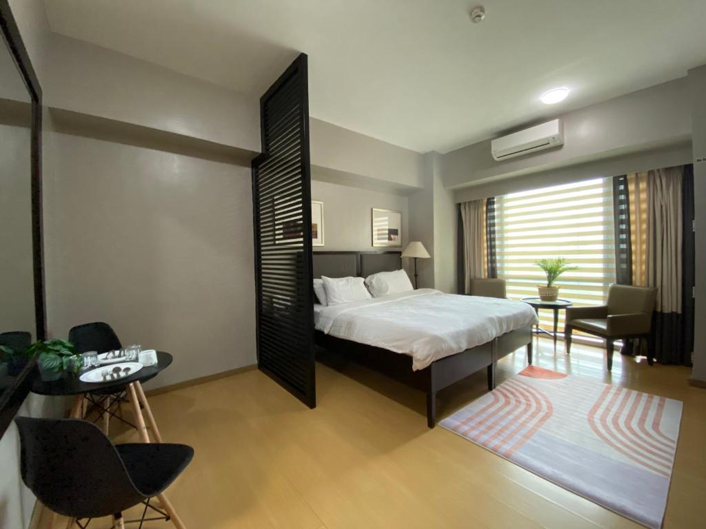 1 dormitorio con 1 cama, mesa y sillas en Avant at the Fort by Urban Realty en Manila