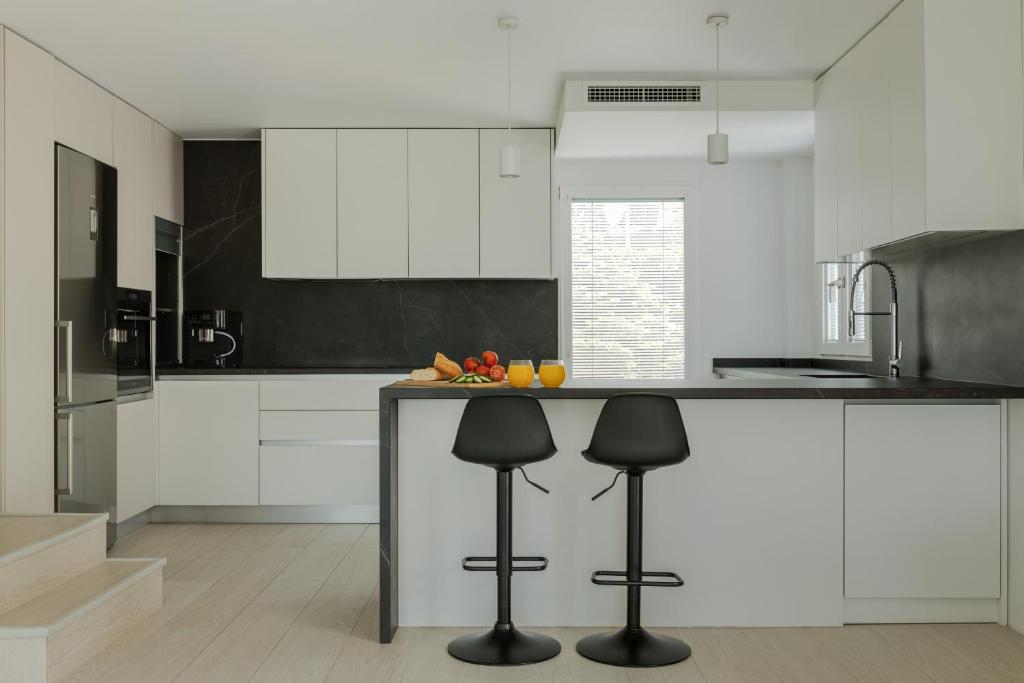 une cuisine avec des placards blancs et un comptoir avec des tabourets dans l'établissement casa matteo, à Finestrat