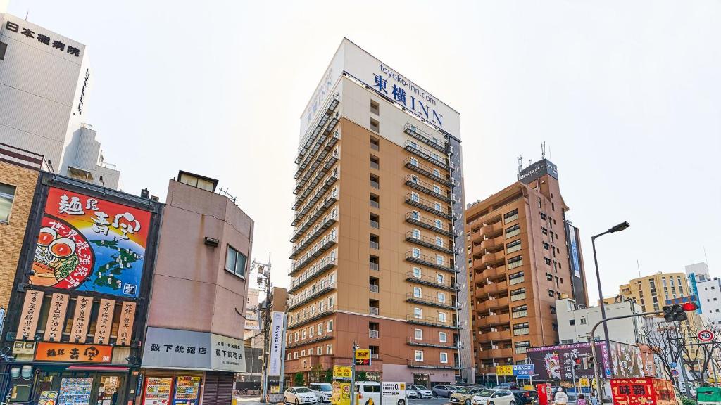 een drukke stadsstraat met hoge gebouwen en auto's bij Toyoko Inn Osaka Nippombashi Bunraku Gekijo Mae in Osaka