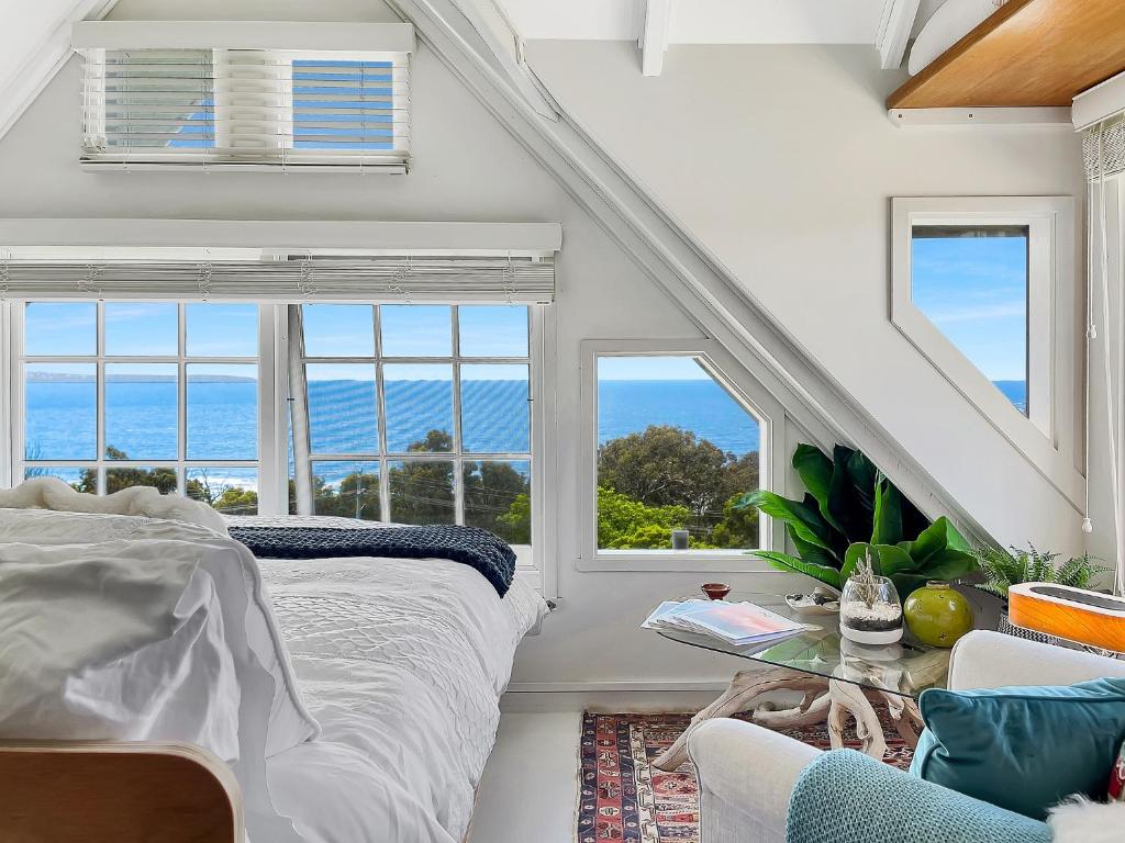a bedroom with a bed and a view of the ocean at Riversong & Sea Dreaming in Pambula Beach