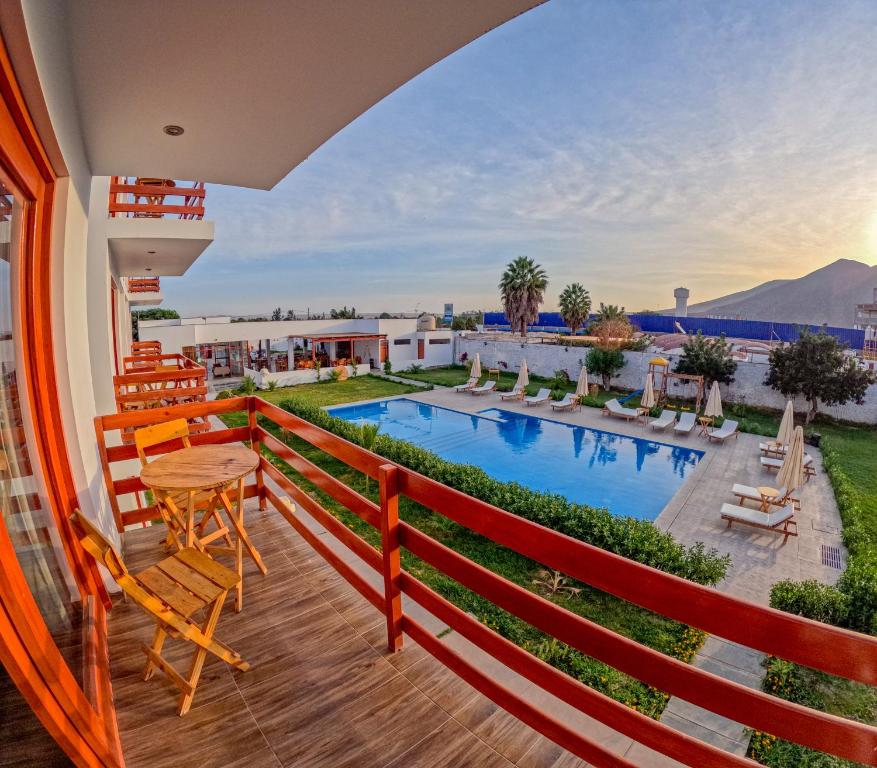 a balcony with a table and chairs and a swimming pool at Hotel La Colina in Ica