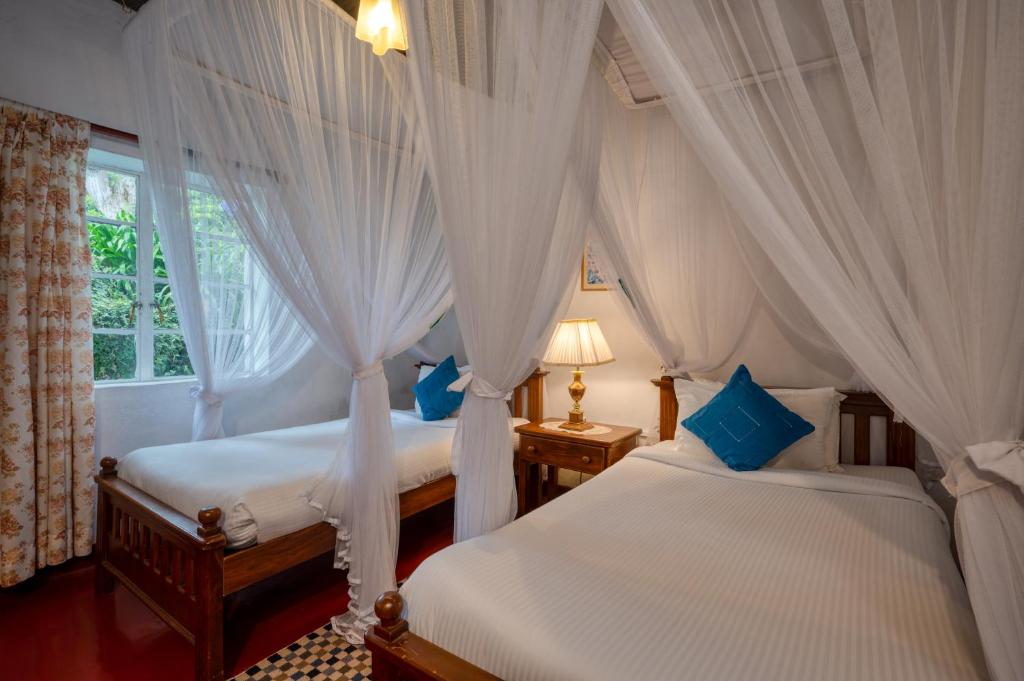 2 Betten in einem Schlafzimmer mit weißen Vorhängen in der Unterkunft Kelburne Estate in Haputale