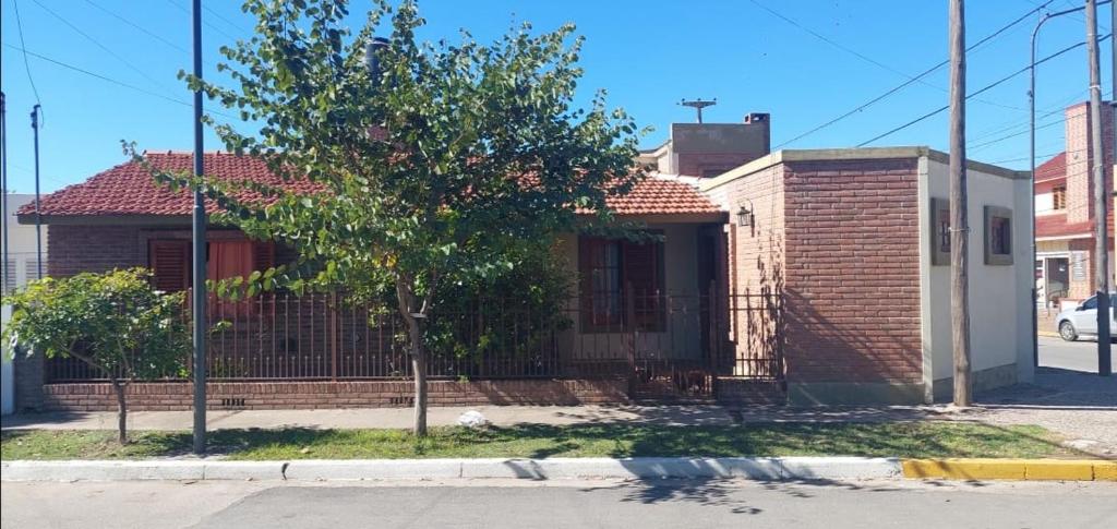 uma casa de tijolos com uma árvore em frente em La casa de Lily em Alta Gracia