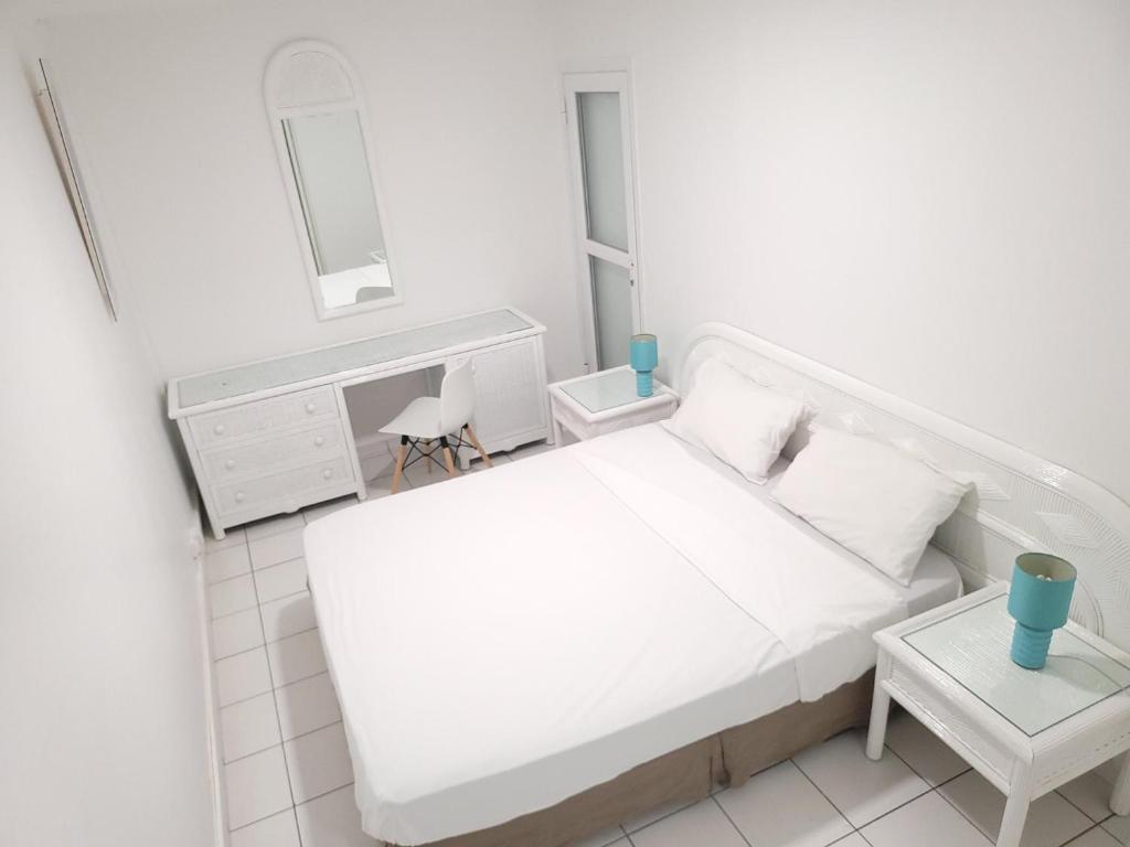 a white bedroom with a white bed and a desk at LE MD 43 in Pointe-à-Pitre