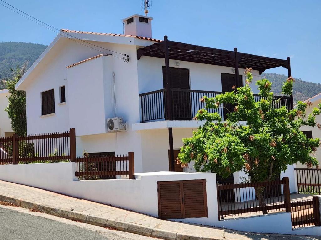 una casa blanca con una valla y un árbol en Seaclusion Vacation Villa, en Pomos