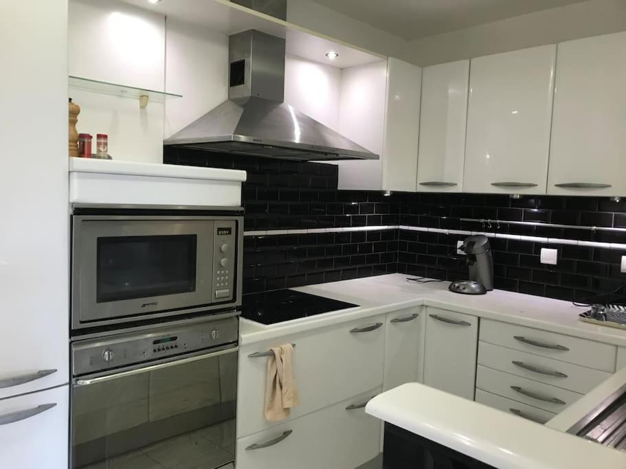 La cuisine est équipée de placards blancs et d'un four avec plaques de cuisson. dans l'établissement Appartement 100 m2 hyper centre Saint-Raphaël, à Saint-Raphaël