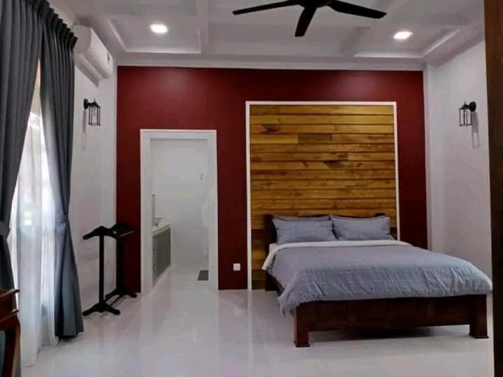 a bedroom with a large bed with a wooden headboard at Inap Kota sang rimba in Kuala Terengganu