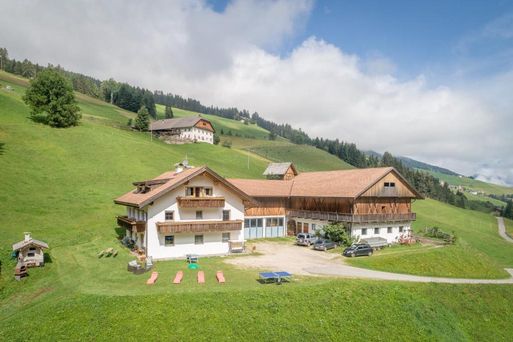 a large house on top of a green hill at Bad Bergfallerhof in Valdaora