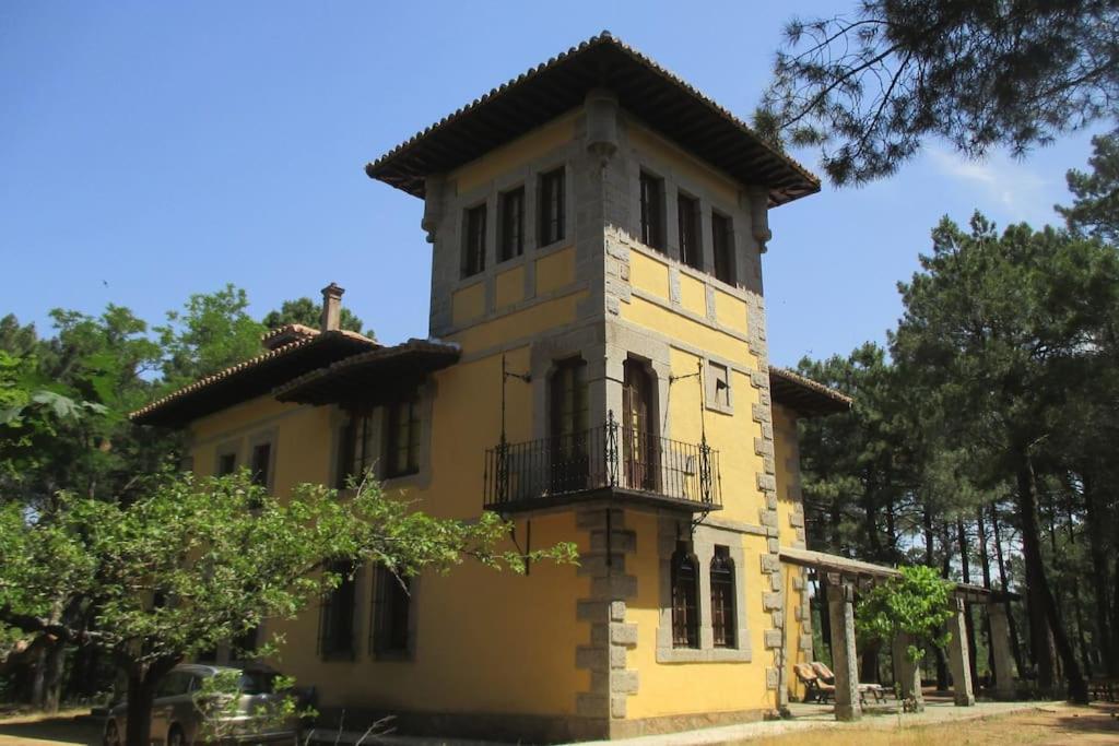 a yellow building with a balcony on top of it at QUINTA ARENlLLAS Palacete en una finca privada de 7 hectáreas de pinar in Navalperal de Pinares