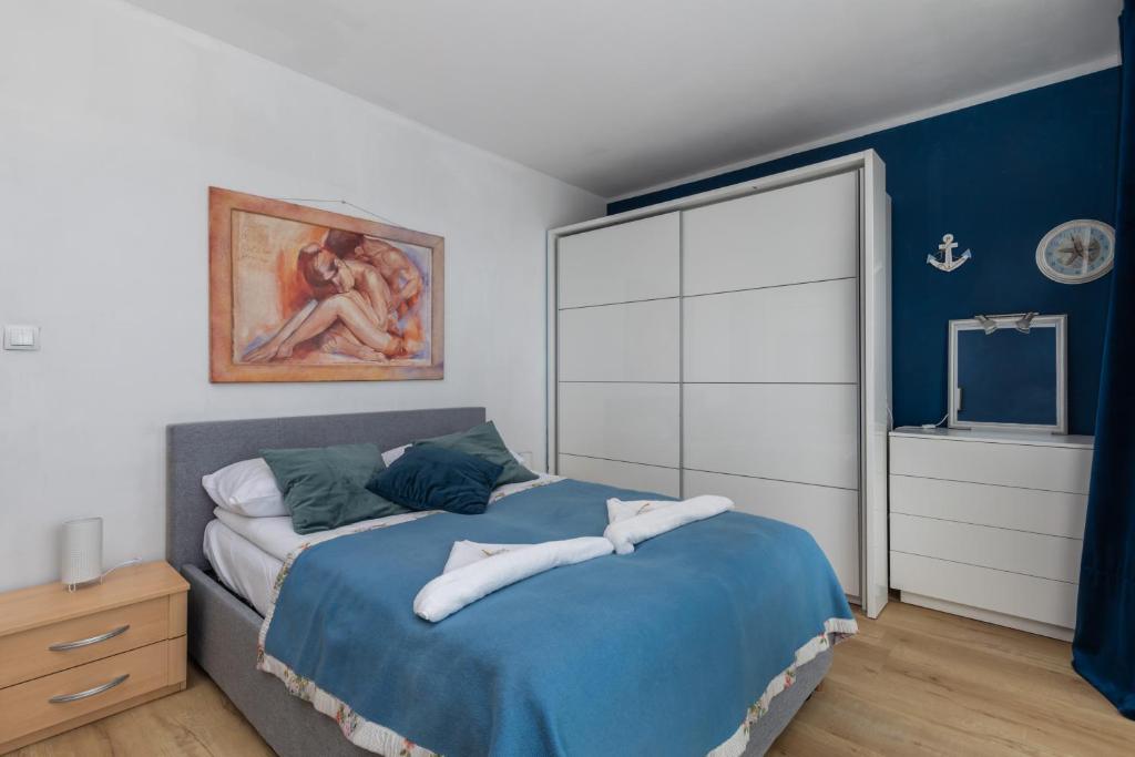a bedroom with a bed and a painting on the wall at Resort Kropli Bałtyku Apartments by Renters in Darłowo