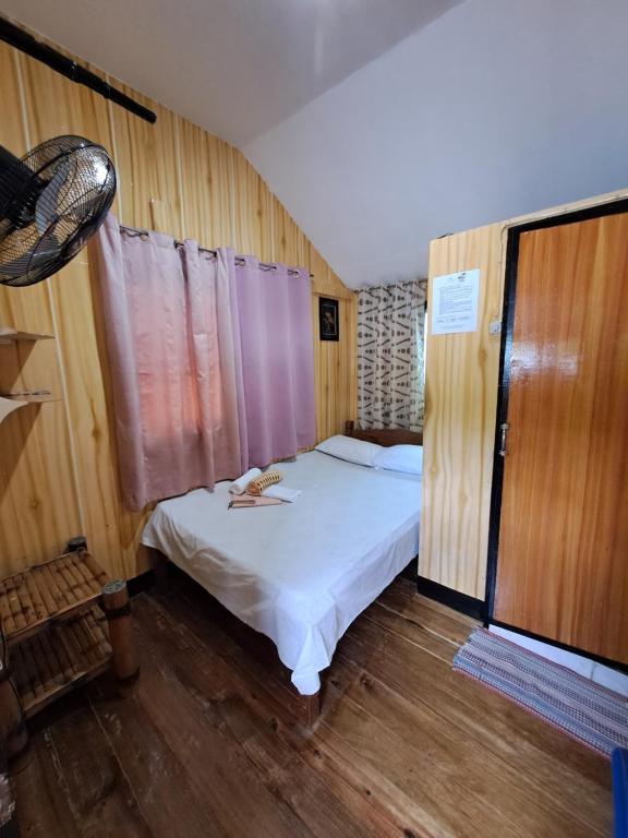 a small bedroom with a white bed and wooden walls at Blessed Inn in San Miguel