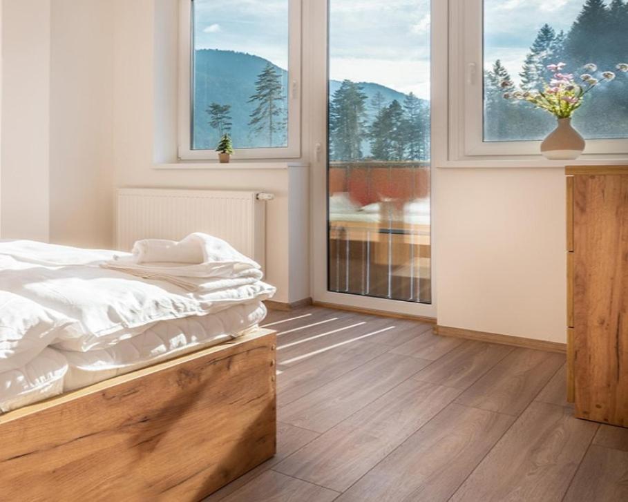 um quarto com uma cama e uma grande janela em Zaži Apartmány Liptovský Ján em Liptovský Ján