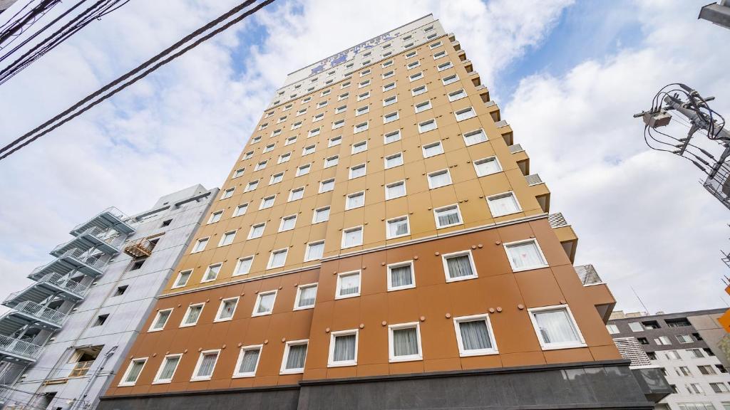 um edifício amarelo alto com janelas brancas em Toyoko Inn Matsudo eki Higashi guchi em Matsudo