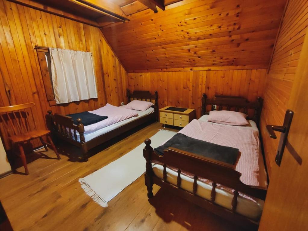 a bedroom with two beds in a wooden cabin at Holiday Home Ljuban in Risovac
