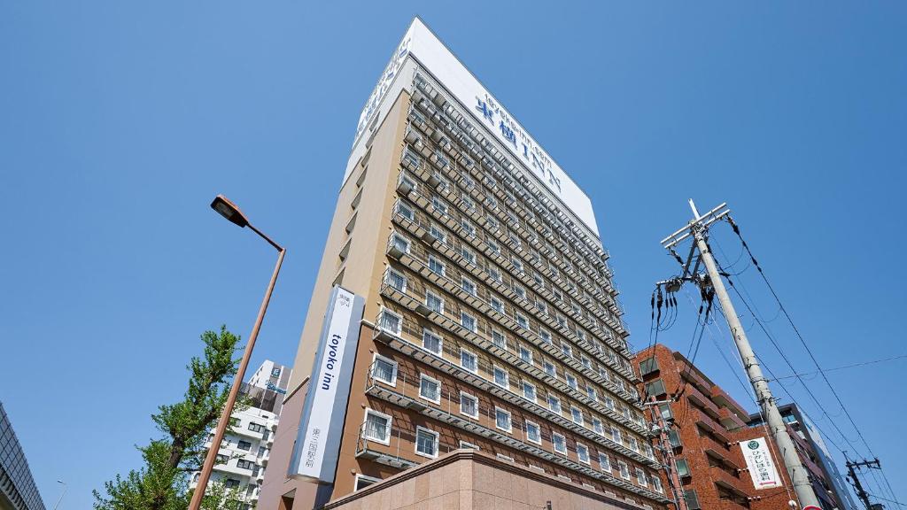 Um edifício alto com uma grua à frente. em Toyoko Inn Shin-osaka Higashi-mikuni Ekimae em Osaka