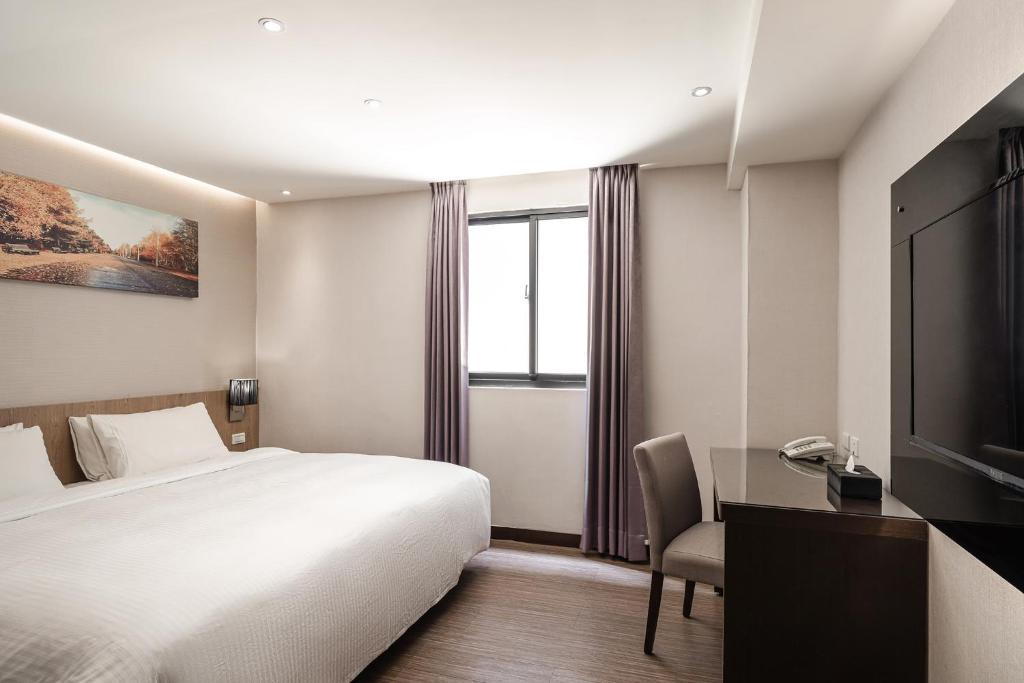高雄市にあるHotel Yoshiのベッド、デスク、テレビが備わるホテルルームです。
