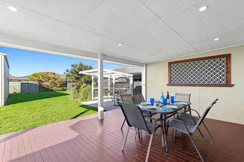 阿勒达拉Fish Cottage Ulladulla - Linen not supplied - 3 bedroom house - sleeps 8 - pet friendly的露台上摆着桌椅的餐厅
