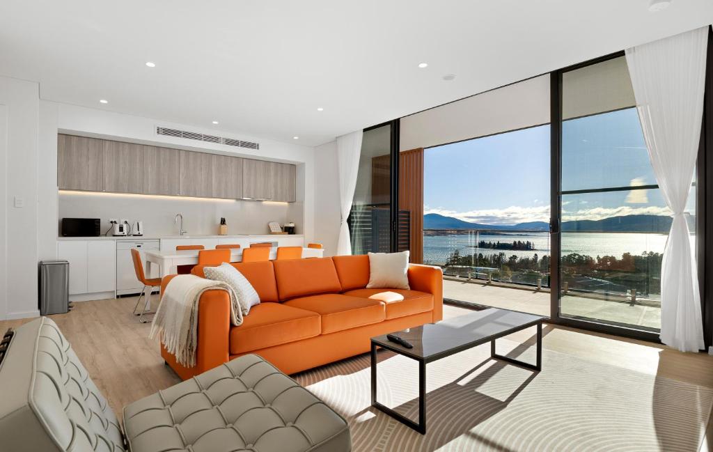 an orange couch in a living room with a view at Lake View Suites Jindabyne in Jindabyne