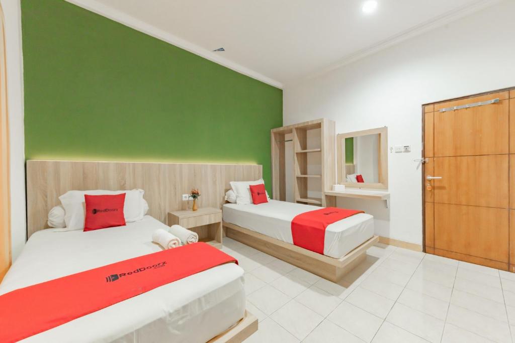 - une chambre avec 2 lits et un mur vert dans l'établissement RedDoorz Syariah near Taman Bekapai 2, à Klandasan Kecil