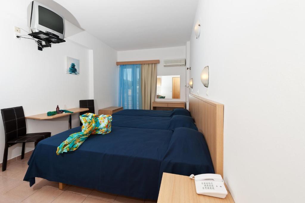 Pokój hotelowy z niebieskim łóżkiem i biurkiem w obiekcie Europa Hotel w mieście Rodos