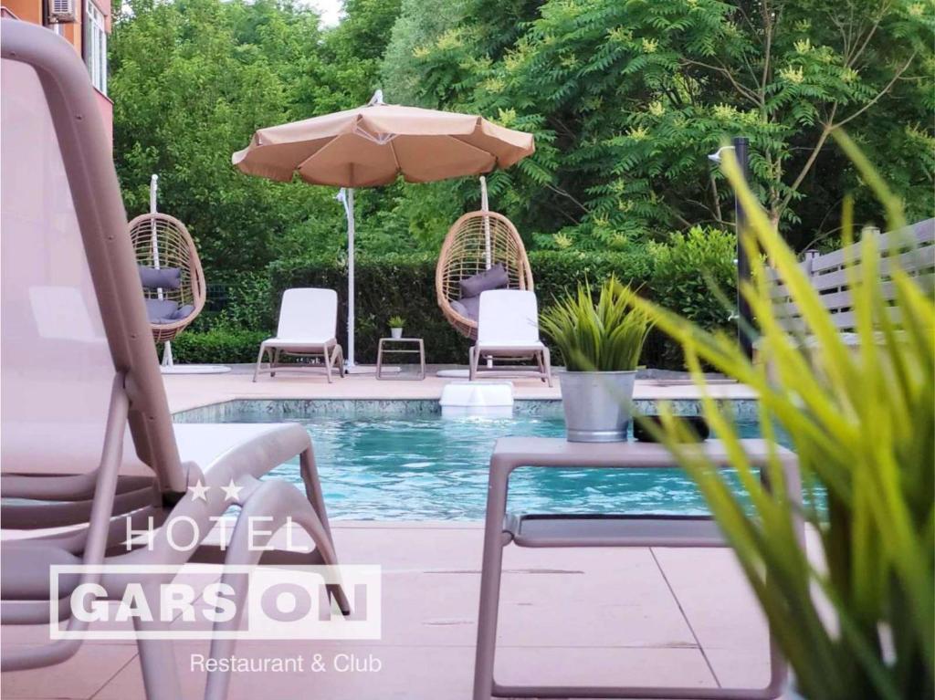 einen Pool mit Stühlen, einem Sonnenschirm und einem Tisch in der Unterkunft GarsON in Kardschali