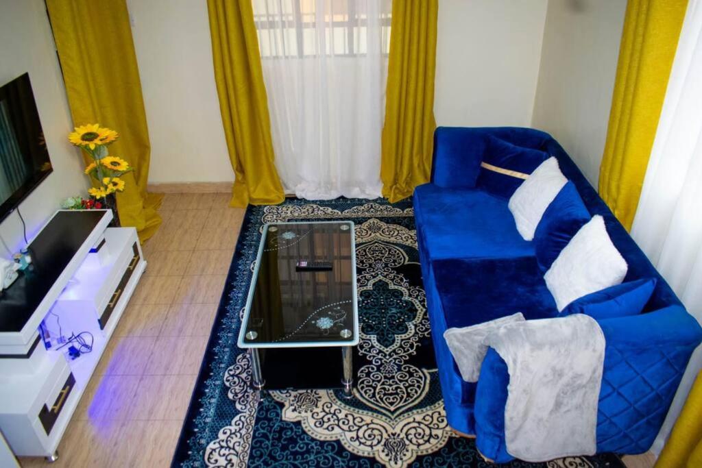 a living room with a blue couch and a tv at BELEEN HOMES in Limuru
