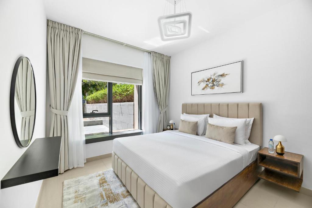 a white bedroom with a bed and a window at Designer 1BR 29 Boulevard Downtown Dubai Near Burj Khalifa in Dubai