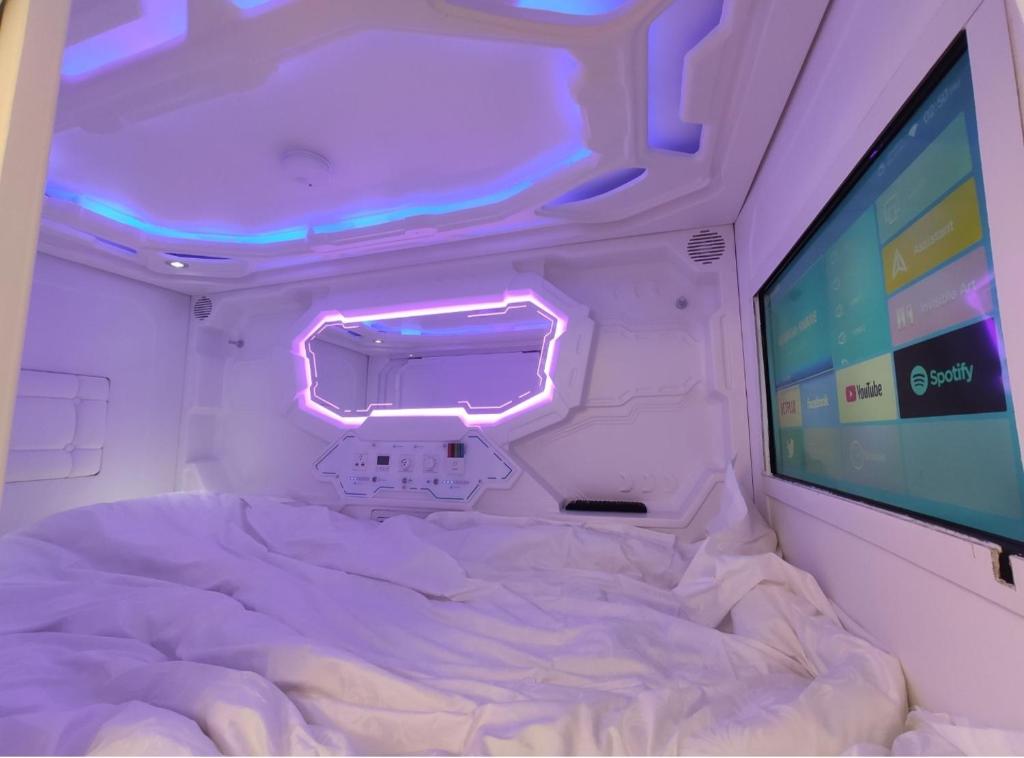 Cette chambre comprend un lit et un grand écran. dans l'établissement CAPSULES & Dormitory BH, à Jérusalem