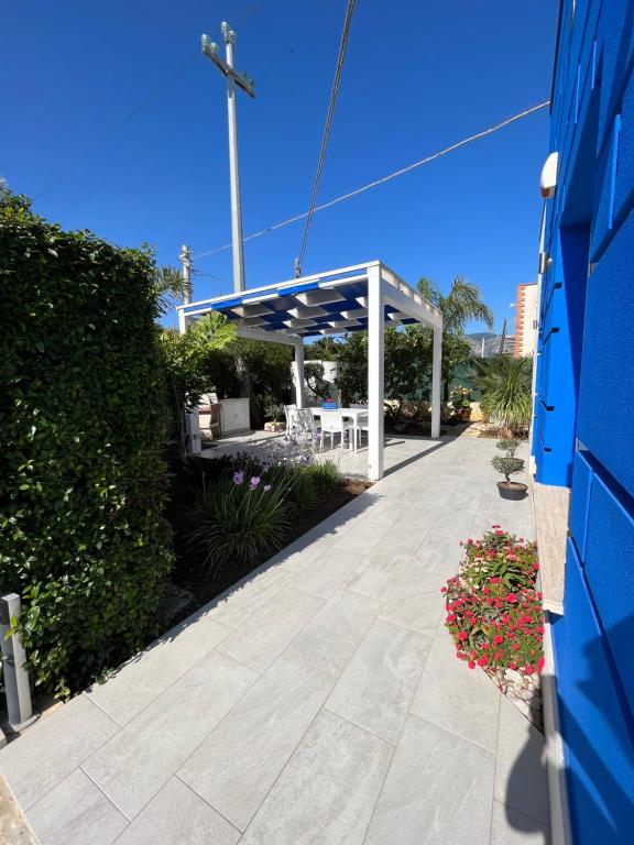 un pavillon avec un banc et des fleurs sur un trottoir dans l'établissement Villetta Azzurra, à Alcamo Marina