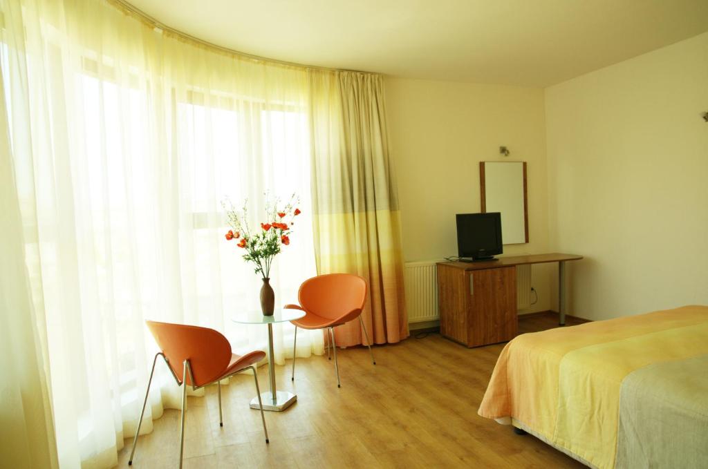 a bedroom with a bed and a table with chairs and a vase of flowers at Hotel Sany in Primorsko