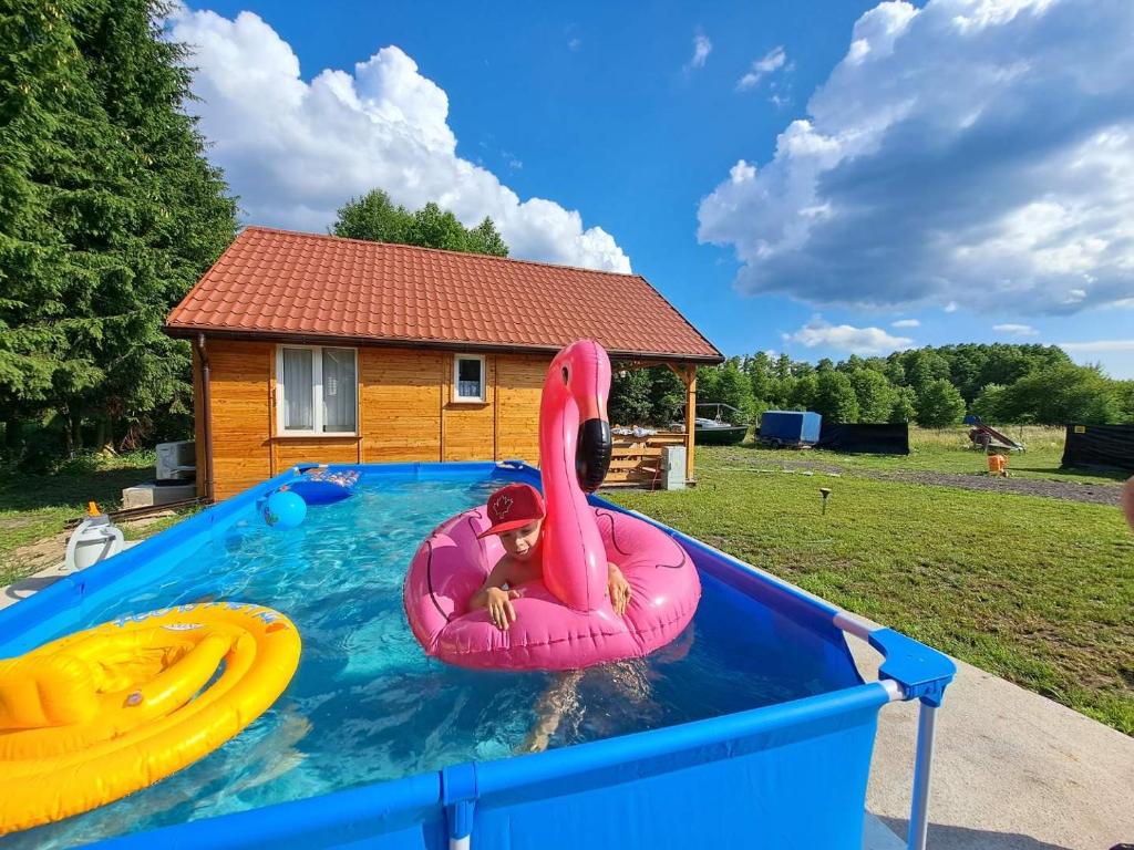 dziecko w różowej tratwie w basenie w obiekcie Domki Snopki w Piszu