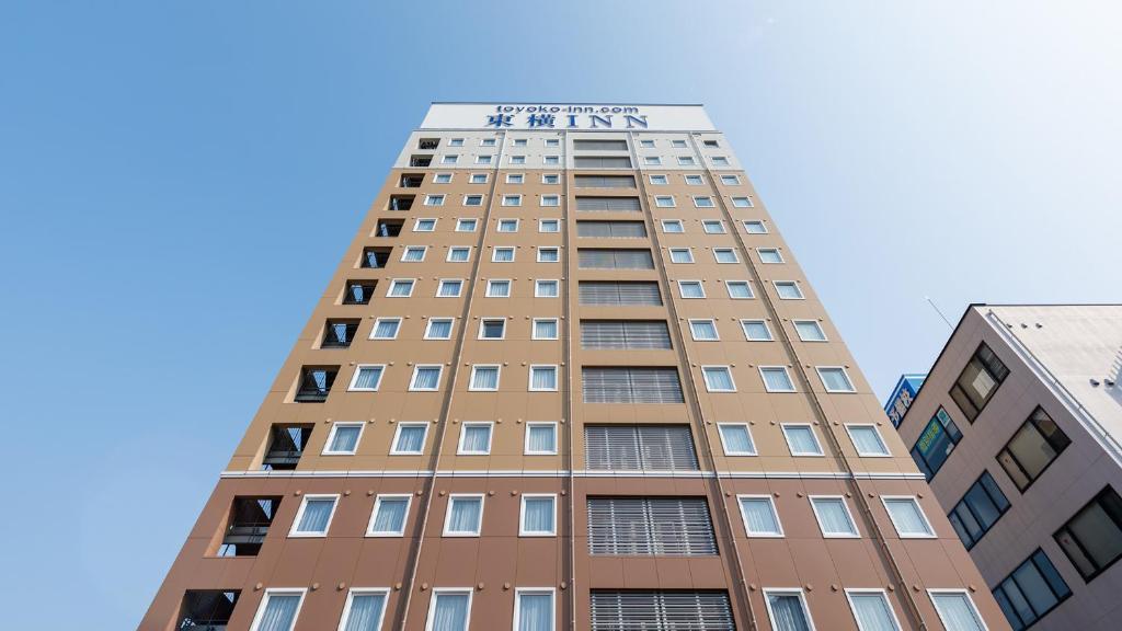 een hoog gebouw met een bord erop bij Toyoko Inn Tsu eki Nishi guchi in Tsu