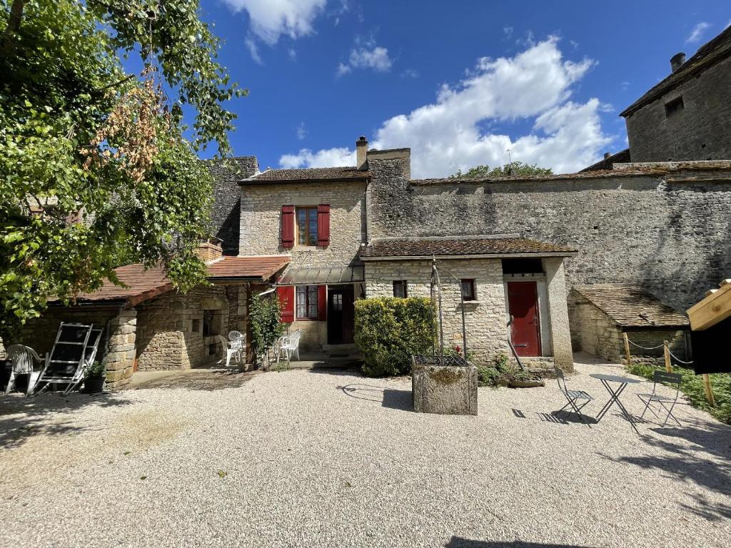 een oud stenen huis met rode ramen en een oprit bij L'Ouvrée, chaleureux en famille ou entre amis in Saint-Aubin
