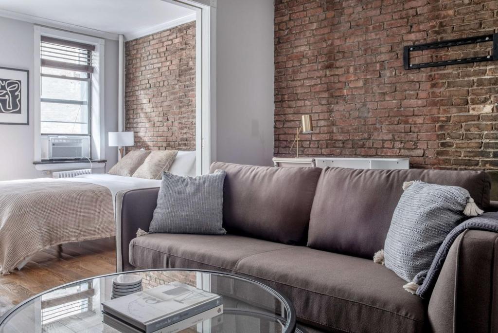 un soggiorno con divano e muro di mattoni di West Village 1BR w In-Unit WD NYC-1177 a New York